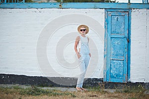 Pretty slim tan blonde stylish woman in straw hat and sunglasses posing