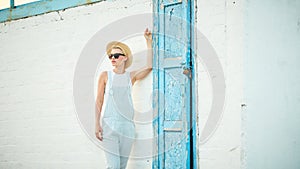 Pretty slim tan blonde stylish woman in straw hat and sunglasses posing