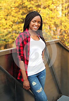 Pretty smiling african woman wearing red checkered shirt in sunny autumn