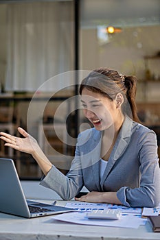 Pretty smiling asian female accountant working on laptop computer in modern office