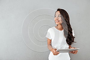 Pretty smiling asian woman holding tablet computer