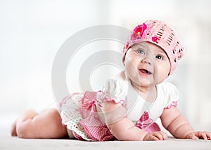 Pretty smiling baby girl lying on stomach and looking up