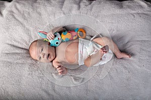 Pretty smiling baby girl and toy rabbit lying in light background