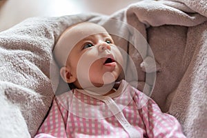 Pretty smiling baby girl and toy rabbit lying in light background