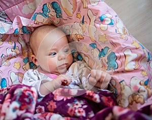 Pretty smiling baby girl and toy rabbit lying in light background