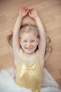 Pretty smiling ballet chilg girl in white tutu on floor