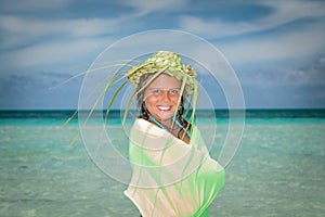 Pretty smiling beautiful little stylish girl on the beach against ocean and blue sky background