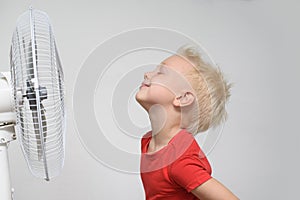 Pretty smiling blond boy in red shirt and closed eyes enjoying the cool air. Summer concept