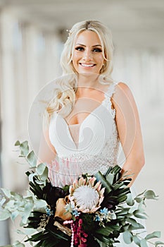 Pretty smiling bride with the wedding bouquet in boho style