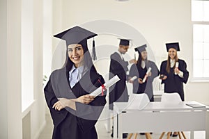 Pretty smiling caucasian girl student university graduate in mantle and bonet standing with diploma