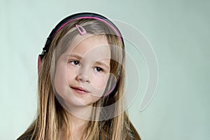 Pretty smiling cild girl listening to music in big pink earphones