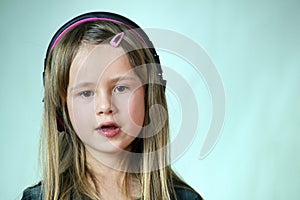 Pretty smiling cild girl listening to music in big pink earphones