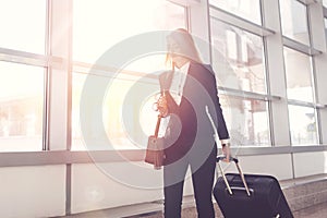 Pretty smiling female flight attendant carrying baggage going to airplane in the airport