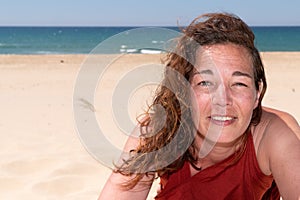 Pretty smiling forties brunette woman on beach sand aside copy space