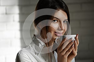 Pretty smiling girl drinking coffee in the morning.