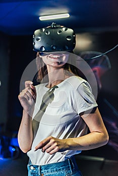 Pretty smiling girl touching her head wearing the virtual reality helmet