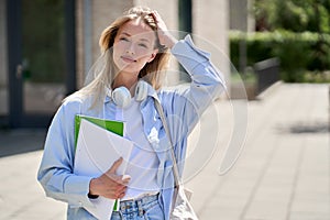Pretty smiling girl university student holds notebooks stands outdoor, portrait.