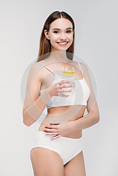 pretty smiling girl in white lingerie holding glass of water