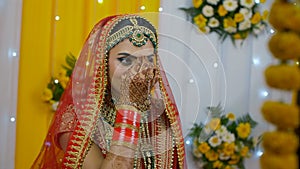 A pretty and smiling Indian bride putting on Bindi while getting ready for her marriage