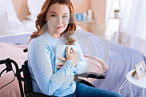 Pretty smiling paralyzed woman holding a book