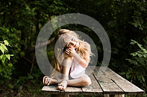 Pretty smiling pensive girl sitting on the old bridge