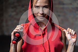 Pretty smiling sporty young woman hold skipping rope around neck.