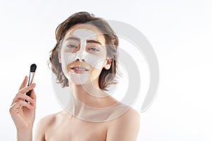Pretty smiling woman with face mask and brush