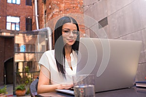 Pretty smiling woman in trendy spectacles professional marketing specialist having online conference via laptop computer