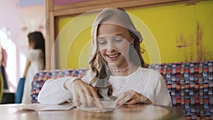 Pretty, smiling and young girl reading the menu in cafe. 4K