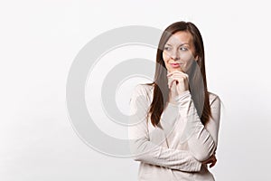 Pretty smiling young woman in light clothes looking aside, put hand prop up on chin isolated on white wall background