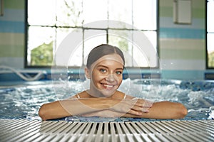 Pretty smiling young woman relaxing in hydro massage pool