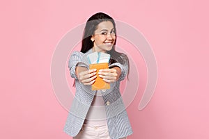 Pretty smiling young woman in striped jacket holding passport, boarding pass ticket isolated on pink pastel wall