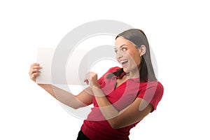 Pretty smiling young woman is surprised with white advertising frame - white A4 paper, empty for text