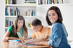 Pretty spanish female student with group of learning students