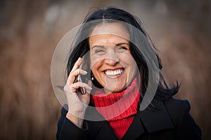 Pretty Spanish Woman Smiling At the camera. Outside having a funny conversation on the phone. Lost in thought.