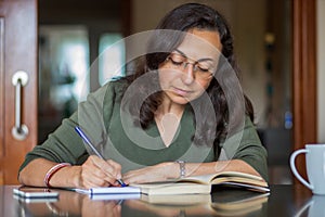 Pretty Spanish woman writing anything on a paper