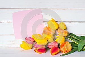 Pretty Spring Tulip Bunch with Pink Card with torn edges on White Rustic Wood Board Table and Background. Horizontal with room or