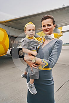 Pretty stewardess and her child posing against the landed airliner