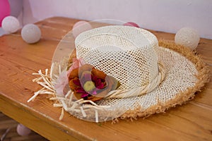 Pretty straw hat with flover on a wood table