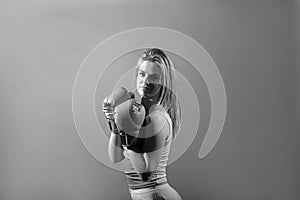 Pretty strong young woman boxer posing  over red background wearing boxing gloves.