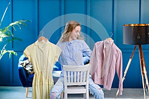 Pretty student girl feeling uncertain about choosing best dress for prom. Young woman decides between two outfits on