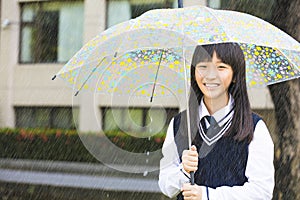 Pretty student girl holding umbrella in the rain