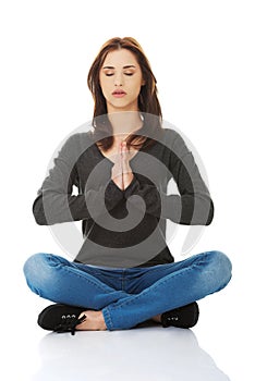 Pretty student girl meditating in lotus pose.