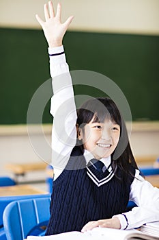 Pretty student girl raising hand in classroom