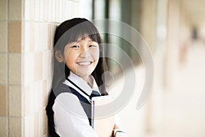 Pretty student holding books in front of classroom