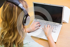 Pretty student studying in the library with laptop