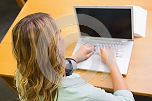 Pretty student studying in the library with laptop