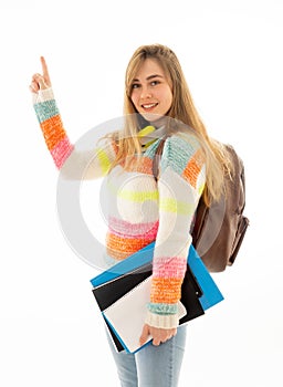 Pretty student teenager woman with schoolbag and books pointing at copy space