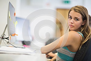 Pretty student working in the computer room looking at camera