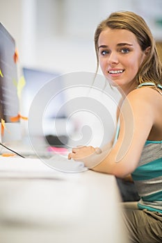 Pretty student working in the computer room smiling at camera